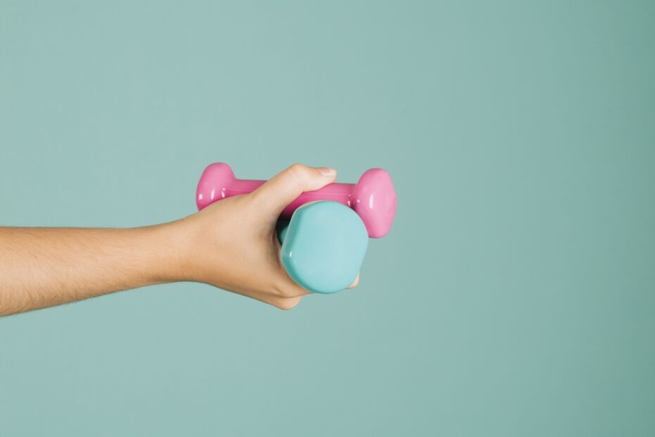 Pessoa segurando halteres coloridos rosa e azul para exercício de fortalecimento