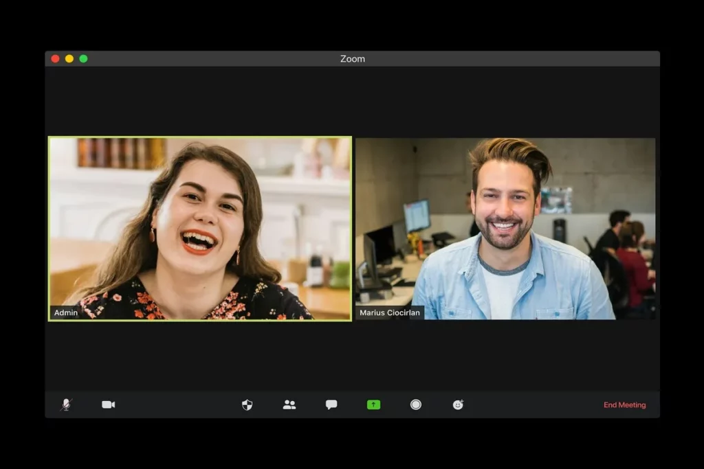 Tela de reunião no Zoom com duas pessoas sorrindo, uma mulher com fundo doméstico e um homem em ambiente de escritório