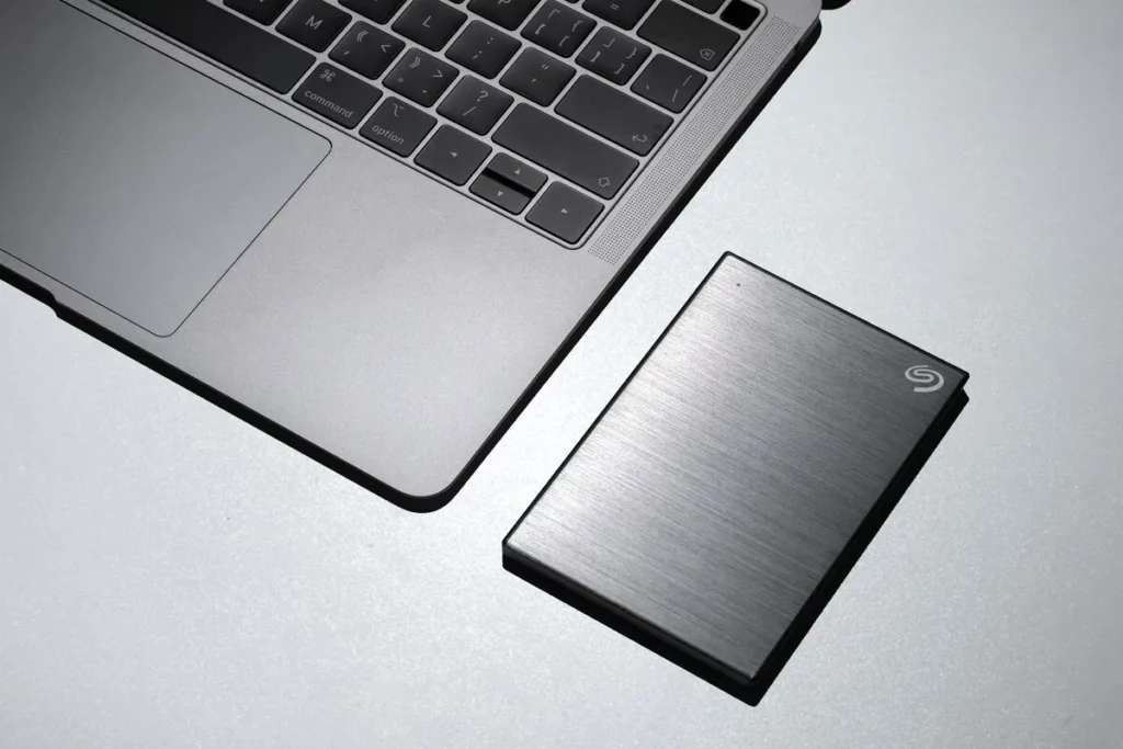 HD externo da Seagate ao lado de um notebook cinza em uma mesa clara