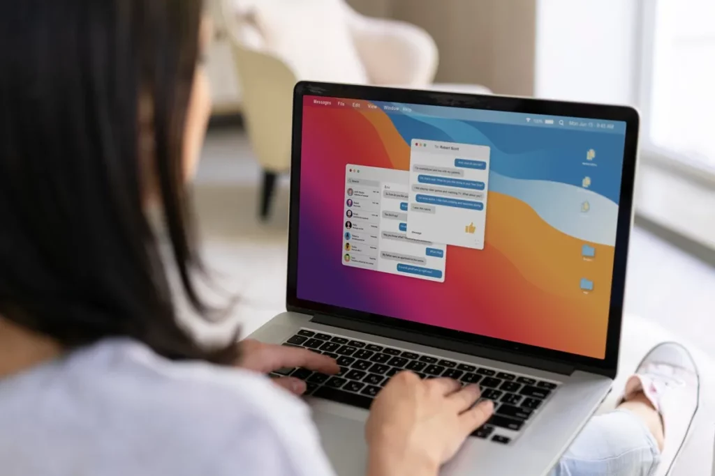 Mulher usando MacBook com janelas de mensagens abertas na tela, conversando com contatos