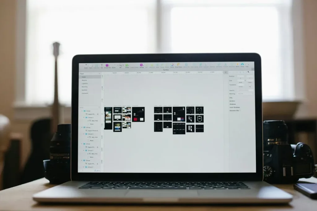 Notebook exibindo um portfólio digital com miniaturas de layouts em ambiente de trabalho com câmeras fotográficas