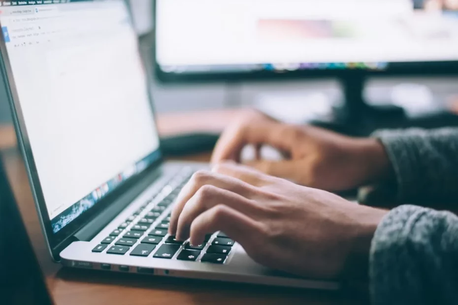 "Mãos digitando rapidamente em um teclado de laptop, simbolizando a busca ativa por soluções sobre como liberar espaço no PC."