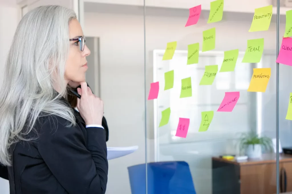Mulher analisando quadro com post-its