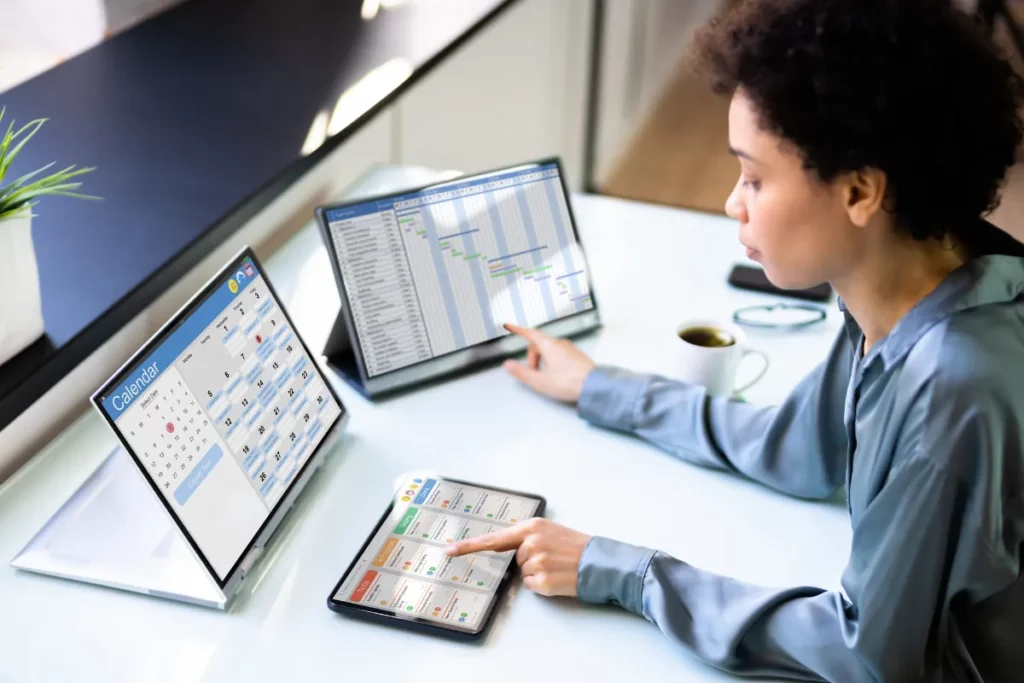 Pessoa sentada, usando 3 dispostivos ao mesmo tempo