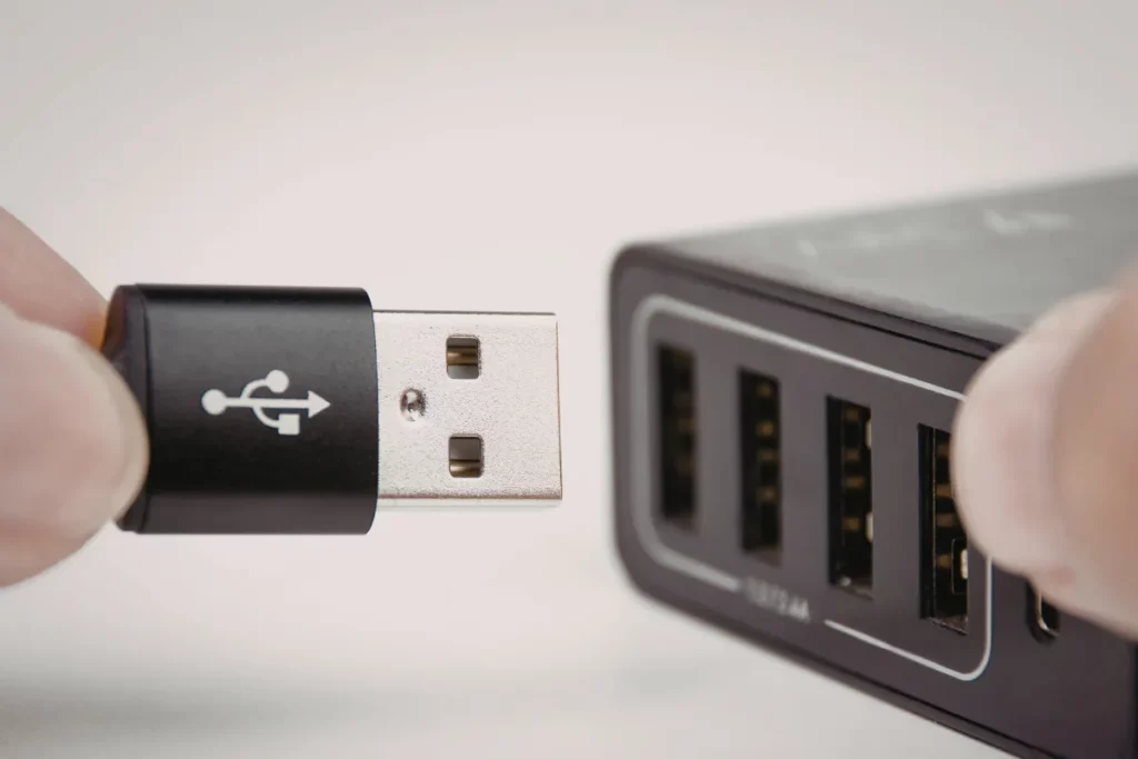 mão segurando um cabo usb próximo das portas de um hub usb com várias entradas