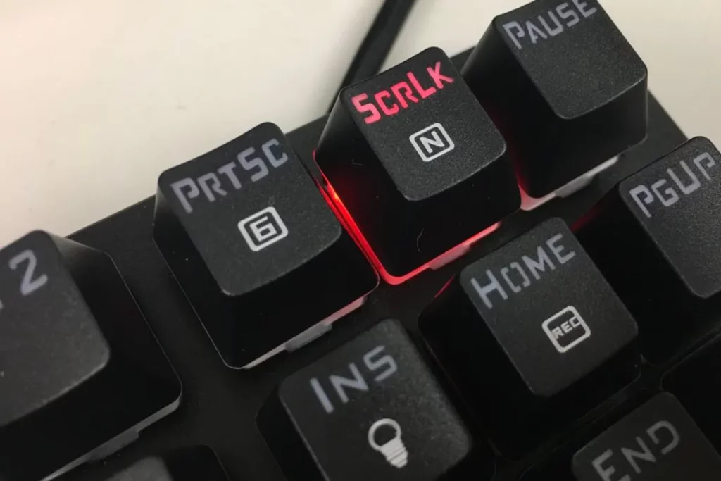 Close de teclado mecânico mostrando a tecla SCRLK iluminada em vermelho ao lado das teclas Print Screen e Pause.