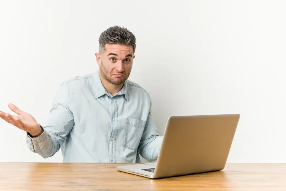 homem sentado em frente ao notebook com a mão no rosto demonstrando frustração ao usar o computador
